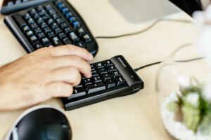 一名男子在数字键盘上打字，桌面上有Goldtouch键盘和鼠标威廉希尔中国官网