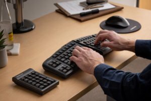 一个人在工作站上，在Goldtouch人体工程学键盘上打字。威廉希尔中国官网此外，图片是一个数字键盘和人体工程学鼠标与鼠标垫。